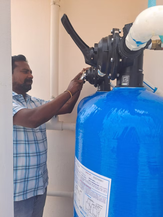 Technician adjusting the control valve on a water treatment tank